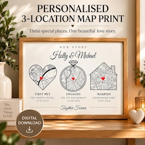 Pode incluir: Uma impressão de mapa personalizada emoldurada intitulada Our Story para Holly e Michael. Apresenta três secções de mapa a preto e branco em forma de coração, anel e casa, cada uma marcada com um coração vermelho, First Met, Engaged, Married.