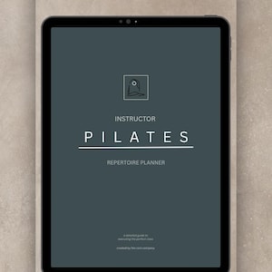 Può includere: Un tablet digitale che mostra una copertina grigio scuro per un Instructor Pilates Repertoire Planner. Il testo recita Instructor Pilates Repertoire Planner, a detailed guide to executing the perfect class, created by the core company.