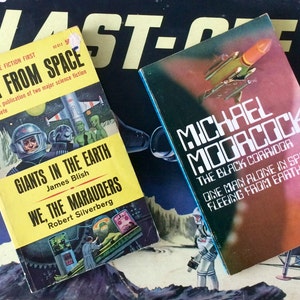 Puede incluir: Dos libros de bolsillo de ciencia ficción vintage con portadas coloridas. El libro de la izquierda se titula "Giants in the Earth" de James Blish y "We, The Marauders" de Robert Silverberg. El libro de la derecha se titula "The Black Corridor" de Michael Moorcock. Los libros están sobre un fondo negro con un letrero amarillo y negro "Blast-Off!"