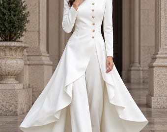 May include: A white long-sleeved jumpsuit featuring a high collar and a row of gold buttons down the front. The garment includes an attached floor-length overskirt with a draped, open-front design that reveals wide-leg trousers underneath.