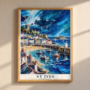 May include: A framed art print depicting the coastal town of St. Ives, Cornwall, featuring a harbor with small boats, a lighthouse, and buildings under a dramatic, textured blue sky. The text ST IVES CORNWALL is printed at the bottom.