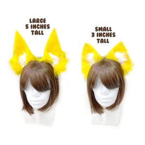 May include: Two pairs of yellow fox ears with white tips. The larger pair is 5 inches tall and the smaller pair is 3 inches tall.