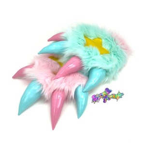 May include: A pair of fuzzy pink and blue claw-shaped hand warmers with a yellow star on the blue one.
