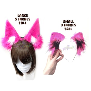 May include: Two pairs of pink and black faux fur cat ears. The larger pair is 5 inches tall and the smaller pair is 3 inches tall.