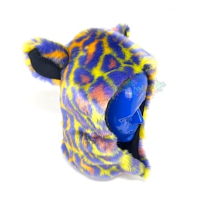 May include: A purple, yellow, and orange leopard print hooded hat with black ears. The hat is made of faux fur and is worn on a blue mannequin head.