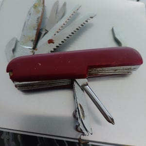 Rotes, klappbares Schweizer Taschenmesser mit Schere, Säge, Korkenzieher und Dosenöffner.