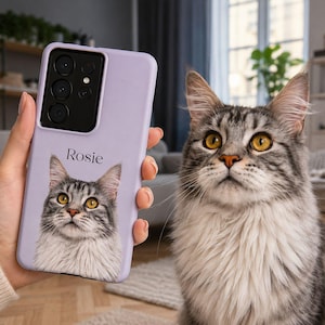 Op de afbeelding: Een lichtpaarse smartphonehoes met een aangepast portret van een grijze en witte cyperse kat met gele ogen. De naam Rosie is in zwarte tekst boven de kattenillustratie gedrukt. De hoes heeft een zwarte uitsparing voor de cameralenzen.