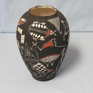 May include: Black ceramic vase with a white and red geometric design featuring birds and insects.