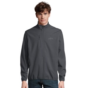 Puede incluir: Una chaqueta softshell de color gris oscuro con cremallera frontal completa, cuello alto y mangas largas. La chaqueta incluye un bolsillo vertical con cremallera en el pecho derecho y dos bolsillos inferiores con cremallera, con un pequeño logotipo gráfico de montaña.