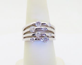 May include: A silver ring with five bands and multiple small round clear stones.