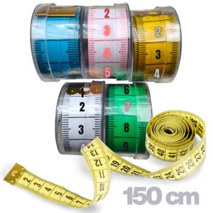 Puede incluir: Una colección de cinco cintas métricas retráctiles en azul, blanco, rosa, amarillo y verde, cada una en una caja de plástico transparente. Una cinta amarilla está desenrollada, mostrando marcas negras y el texto 150 cm en la esquina.
