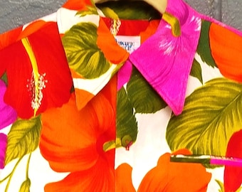 May include: A white short-sleeved shirt with a vibrant floral print featuring large red, orange, and pink hibiscus flowers with green leaves.