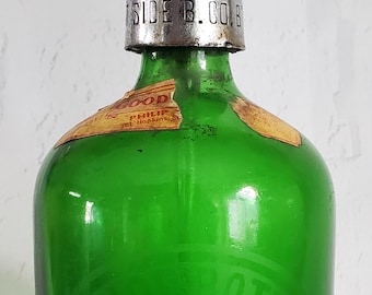 May include: A green glass bottle with a silver metal top and a label that reads "GOOD PHILIP 101 Hawkins St.". The bottle has a circular design embossed on the side.