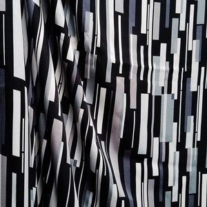 May include: Black and white fabric with a geometric pattern of vertical and horizontal lines and rectangles. The fabric has a subtle sheen and a smooth texture.