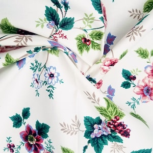 May include: White fabric with a floral pattern featuring pink, red, blue, and green flowers. The fabric has a subtle sheen and a soft texture.