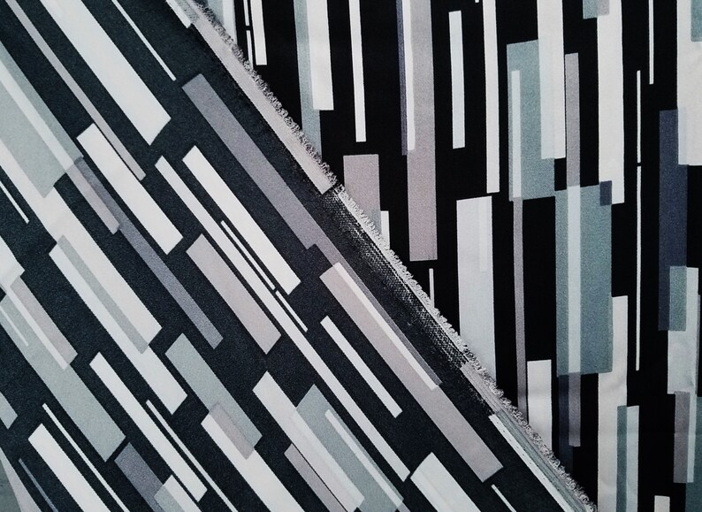 May include: Two pieces of fabric with a geometric pattern of black, white, and gray stripes. The fabric is cut at a diagonal angle.