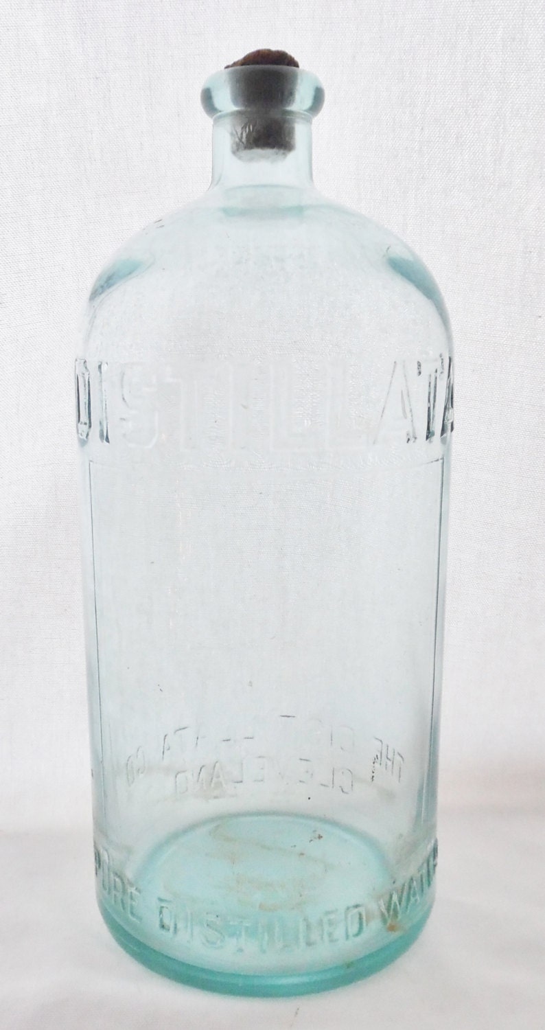 May include: A clear glass bottle with a cork stopper. The bottle is labeled "DISTILLED WATER" and "THE CLEVELAND DISTILLING CO."