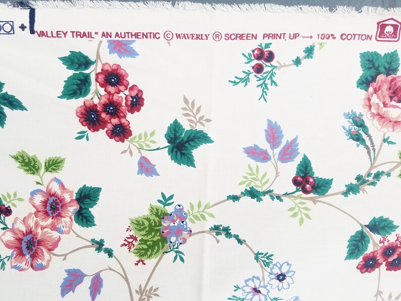 May include: White fabric with a floral pattern featuring pink, red, and blue flowers with green leaves. The fabric has the text "Valley Trail" "An Authentic" "Waverly" "Screen Print, Up" "100% Cotton" printed on it.