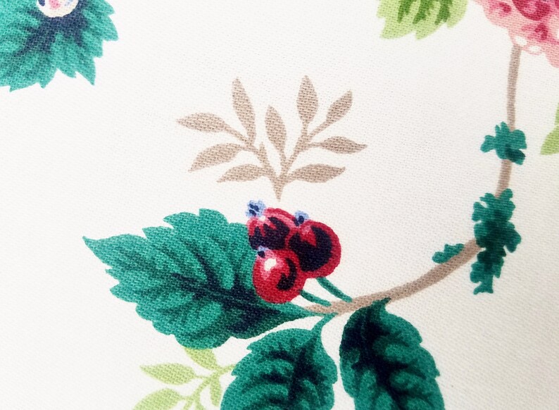 May include: A close-up of a fabric with a floral pattern. The pattern features green leaves, brown branches, and red berries.