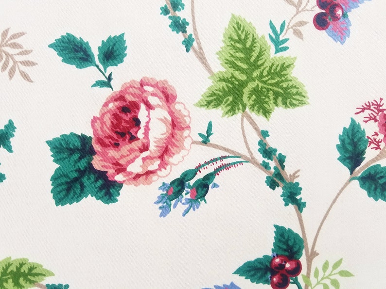 May include: A white background with a pink rose, green leaves, and brown branches. The rose has a red center and is surrounded by smaller blue flowers.