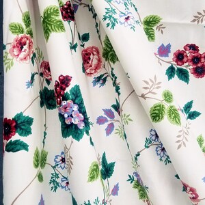 May include: White fabric with a floral pattern featuring pink, red, and blue flowers, green leaves, and brown vines.