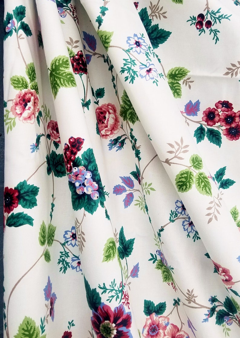 May include: White fabric with a floral pattern featuring pink, red, and blue flowers, green leaves, and brown vines.