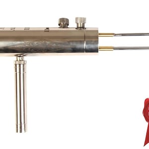 May include: A metallic, pistol-shaped tool with a cylindrical body featuring Roman numerals I through V, two knurled adjustment knobs on top, and two parallel prongs extending from the front. A vertical handle extends downward. A red seal icon reads PATENTLI ÜRÜN.