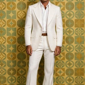 May include: A white suit consisting of a two-button blazer and matching trousers, worn with a white collared shirt and a brown leather belt. The ensemble features wide lapels and flared pant legs. The text MS MILANO STITCH is visible.