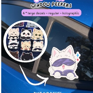 May include: A collection of 4-inch JJK Cat window peeker decals featuring various illustrated cat characters in regular and holographic finishes. One white cat character wearing dark sunglasses and a purple hoodie is applied to a blue car window.