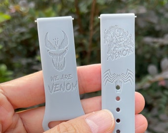 May include: Two gray silicone watch bands with a Venom design. One band has the text "We are Venom" and the other has a Venom character graphic.