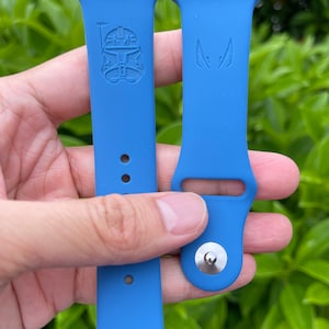 Puede incluir: Dos correas de reloj de silicona azul con una hebilla plateada. Una correa tiene una imagen en relieve de un personaje de Star Wars, Boba Fett. La otra correa tiene una imagen en relieve de un personaje de Star Wars, Darth Vader.