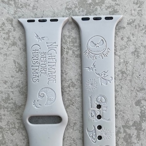 Puede incluir: Dos correas de reloj de silicona blanca con diseños grabados de la película Pesadilla antes de Navidad. Una correa presenta el texto "Nightmare Before Christmas" y una silueta de Jack Skellington. La otra correa presenta la cara de Jack Skellington y el texto "What's This?" junto con otros personajes y símbolos de la película.