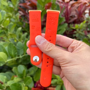 May include: Two orange silicone watch bands with gold accents. One band has the text "Happy Halloween" and the other has a Mickey Mouse pumpkin design.