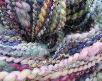 May include: A close-up of a skein of yarn with a variety of colors, including pink, blue, green, and purple. The yarn is made of a soft, fluffy material and has a sparkly finish.