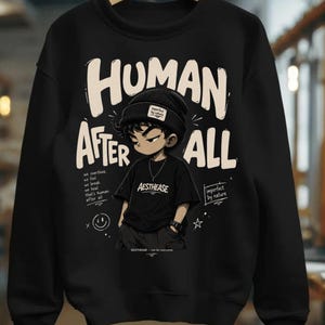 Può includere: Una felpa nera a girocollo con la grafica di una persona con berretto e maglietta, accompagnata dal testo "HUMAN AFTER ALL" e "AESTHEASE". Sono presenti anche le scritte "we overthink, we feel, we break, we heal, that's human after all" e "imperfect by nature".