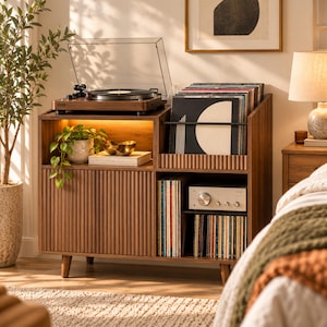 May include: A walnut-toned wooden media console featuring a top surface for a record player, a fluted cabinet door, and open shelving for vinyl records. The unit includes an integrated light, a silver audio amplifier, and a black metal rail.