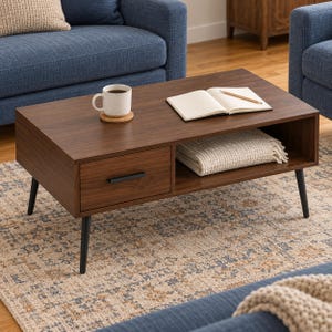 May include: A rectangular dark wood coffee table with four tapered black legs, featuring one drawer with a black handle and an open storage shelf. On the surface sits a white ceramic mug on a cork coaster and an open notebook with a pencil.