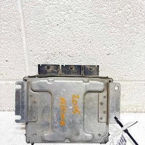 May include: A rectangular silver-colored automotive engine control module with a metallic casing, featuring three black electrical connector ports along the top edge and yellow handwritten text that reads 2015 ALTIMA on the front surface.