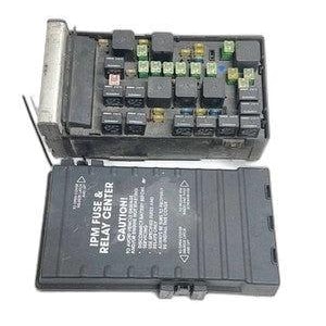 May include: A black automotive IPM fuse and relay center with a removable cover. The unit features multiple black relays and various colored fuses. The cover displays the text IPM FUSE & RELAY CENTER and CAUTION with safety instructions.