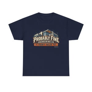 Könnte beinhalten: Ein dunkelblaues Kurzarm-T-Shirt mit einer Grafik eines modernen Gebäudes vor architektonischen Bauplänen. Der Text lautet "PROBABLY FINE ENGINEERING CO." in großen Buchstaben, darunter steht "IT HASN'T FAILED YET.".