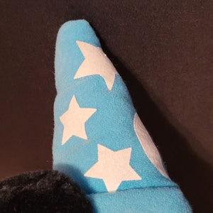 Op de afbeelding: Een blauwe pluche hoed met witte sterren. De hoed is gevormd als een tovenaarshoed.