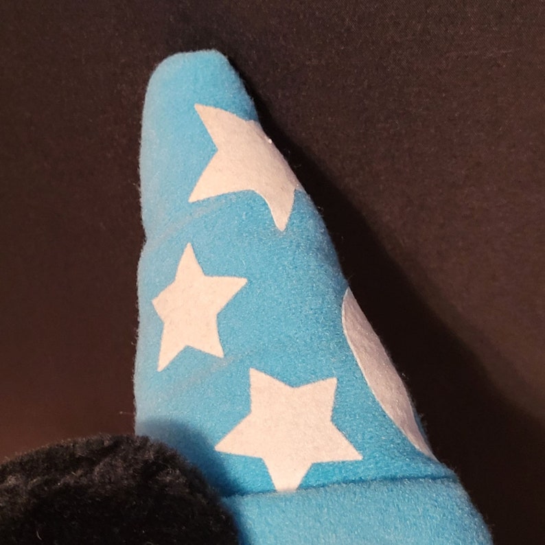 Op de afbeelding: Een blauwe pluche hoed met witte sterren. De hoed is gevormd als een tovenaarshoed.