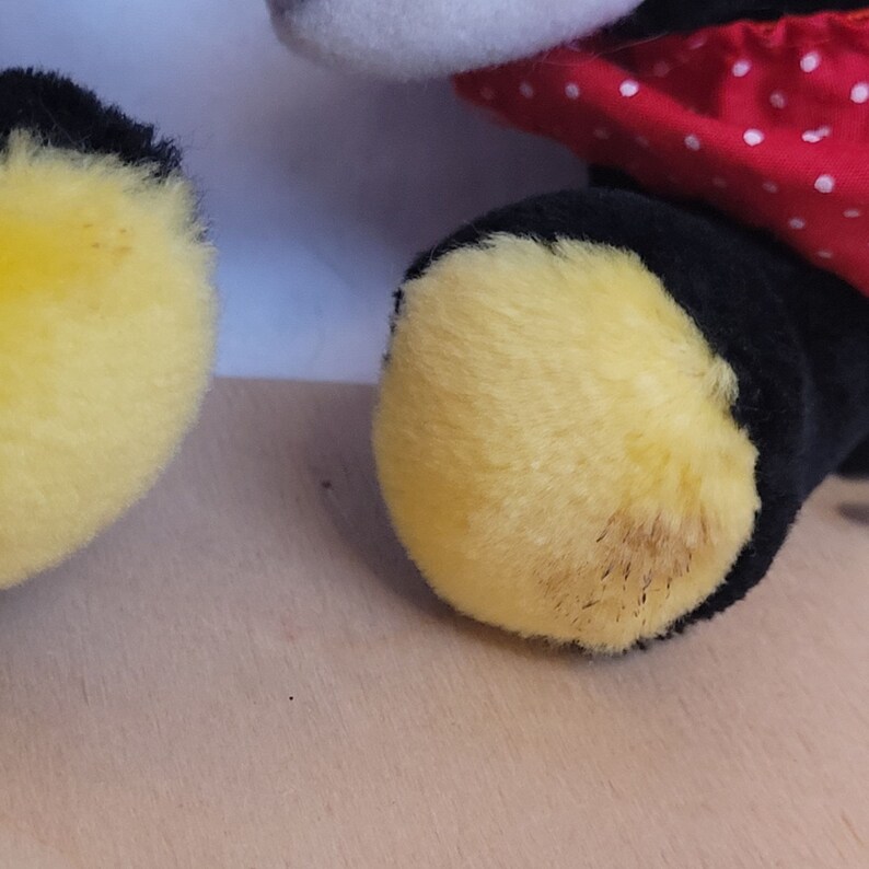 Puede incluir: Primer plano de los pies de un juguete de peluche. Los pies son amarillos y peludos con pelo negro alrededor de los bordes.