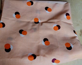 Puede incluir: Tela naranja, blanca y burdeos con un patrón repetido de tres círculos superpuestos. La tela tiene un sutil patrón texturizado.
