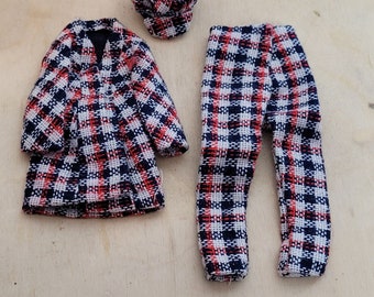 May include: A doll-sized outfit in a black, white and red plaid pattern. The outfit includes a jacket, trousers, and a hat.