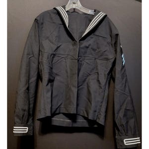 以下が含まれることがあります： 白と黒のセーラーカラーが付いた黒い長袖ジャケット。ジャケットはボタン留めになっており、右側にポケットがあります。ジャケットは袖口に白いストライプが付いています。