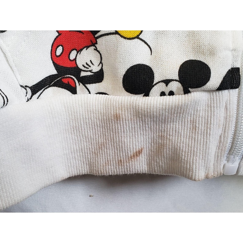 May include: White zippered sweatshirt with a Mickey Mouse print. The sweatshirt has brown stains on the bottom hem.