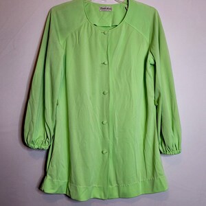 Puede incluir: Una blusa verde lima con botones, mangas largas y cuello redondo. La blusa tiene una etiqueta que dice "Chateau Avenue".