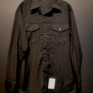 Puede incluir: Una camisa negra de manga larga con botones, dos bolsillos en el pecho y cuello abotonado.