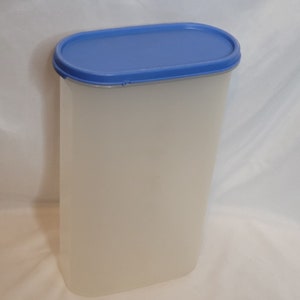 以下が含まれることがあります： 青い楕円形の蓋が付いた透明なプラスチック容器。容器は背が高く円筒形です。